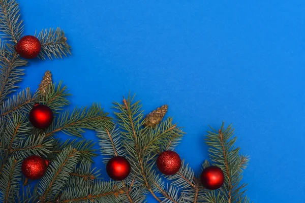 Noel ağacı dalları kırmızı Noel toplarıyla mavi arka planda. Düz yatıyordu.