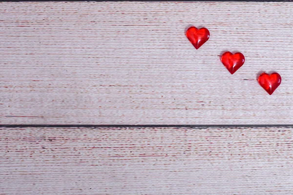 Tres corazones rojos sobre un fondo de madera claro. Vista superior. — Foto de Stock