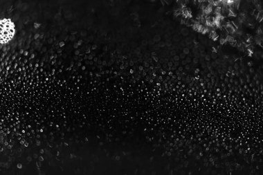 Geceleri camdaki su damlacıkları, karanlık arka plan. Siyah beyaz dokular. Odaklanma ve bulanıklık.
