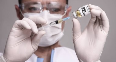 COVID-19. Doktor bilim adamı hastayı aşılamak için aşı topluyor. Erkek araştırmacı laboratuvarda aşıyı test ediyor.. 