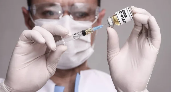 COVID-19. Doktor bilim adamı hastayı aşılamak için aşı topluyor. Erkek araştırmacı laboratuvarda aşıyı test ediyor.. 