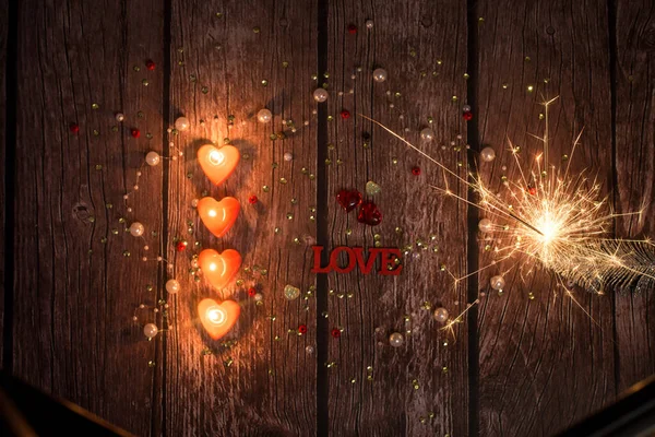 Velas, corazones brillantes, bengalas, sobre un fondo de madera oscura. Fondo para el Día de San Valentín. — Foto de Stock