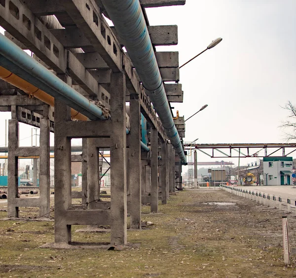 Tubos de ferro em suportes de concreto. a estrada para a instalação industrial. — Fotografia de Stock