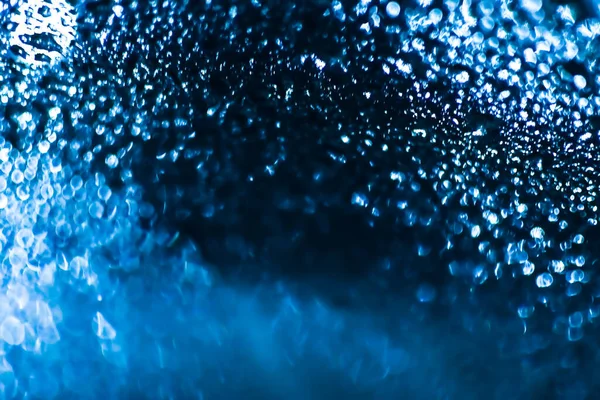 El agua azul cae sobre el fondo. Gotas de agua sobre un fondo de vidrio del coche. Gotas de agua en el vidrio del coche fondo bokeh azul. —  Fotos de Stock