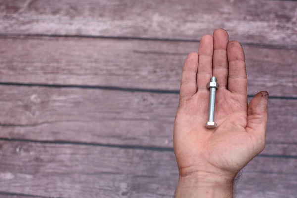 Bolt and nut. In the mans hand, smeared with work, lies a screw with a screwed nut. empty space, — Stock Photo, Image