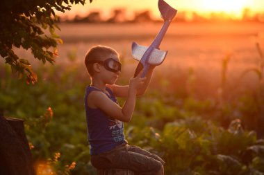 Gün batımında bir çocuk uçakla oynuyor.. 