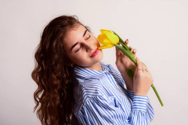 Gözleri kapalı rüya gibi bir kız elinde bir çiçek tutuyor..