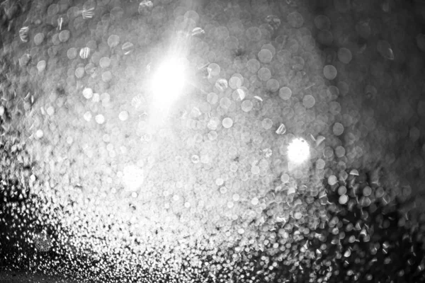 Este esőcseppek az üvegen. Ragyognak a lámpások. Fekete-fehér bokeh. Autós üveg. Defocus. — Stock Fotó