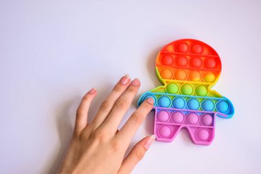 Strese karşı koy. Oyuncağın baloncuk sensörüne parmak basar. Stres önleyici plastik silikon oyuncak beyaz arka planda yakın plan. en üstteki görünüm