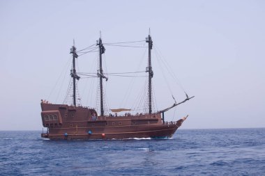 Mavi denizde turistleri taşıyan bir yelkenli.