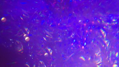abstract purple background. Colorful light reflections and glowing particles in dark abstract background create dreamy, radiant atmosphere with bright neon elements and visual distortion.