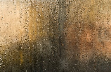wet glass. Tiny beads of moisture decorate fogged window, background. Some drops slide slowly downward, leaving ephemeral trails on glass. abstract backdrop wet glass