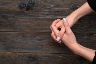 Avuçları ve parmakları birbirine değen iki el birliği sembolize eder. Ahşap arka plan, el ve tırnakların altını çizer. Avuç içleri birbirine kenetlenmiş, ahşap bir yüzeyde yakalanmış eller.. 