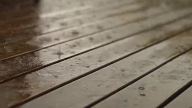 Dağınık su damlaları olan ahşap döşemeler. Yağmur, tahta tahtaları damlalarla kaplayarak yüzeyi yansıtıcı ıslak arka plana çevirir. Yağmurlu hava, yaşam tarzı ayrıntıları.