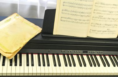 Şık elektronik piyanonun üzerine konmuş notalı bir defter. Hazırlıkları vurguluyor. Kusursuz performans hazırlamak için dizüstü bilgisayar şarttır.