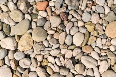 Renkli kumsal çakıl taşları düzensiz şekillerle dolu desenli arka plan oluşturur. Deniz kenarındaki çakıl taşlarının doğal arkaplanı, okyanus şekilli yuvarlak taşlar. Çakıl taşları kıyı ayrıntılarını ve dokusunu tanımlar.