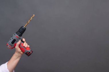 Kablosuz matkap yukarı doğru, uzun metalik ucu olan el tutma aleti, izole edilmiş arka plan. Delgi dikey olarak kaldırıldı, insan eli kavrama kolu, kablosuz araç nötr arkaplanda izole edildi, 