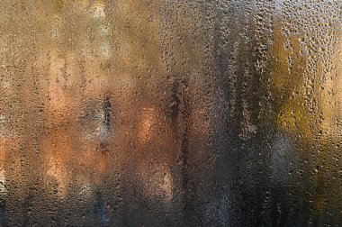 wet glass. Tiny beads of moisture decorate fogged window, background. Some drops slide slowly downward, leaving ephemeral trails on glass. abstract backdrop wet glass