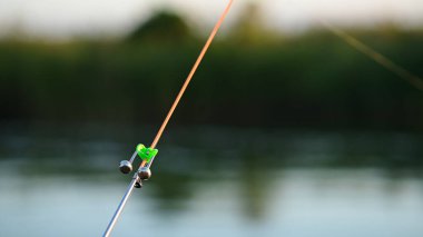 Oltanın ucunda bir uyarı çanı var. Isırık işareti veriyor. bir balıkçılık sahnesi.