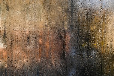 Islak pencere camı, soyut arkaplan. Su damlacıkları sisli cam yüzeyi, nehirler halinde birleşiyor, ötesinin görüntüsünü bozuyor. Yoğunlaşma, soğuk camda organik desenler oluşturur. ıslak cam arkaplan 