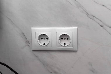 Fayanslı banyo duvarına beyaz çift soket monte edilmiş. Bağlantı ve modern ev aletleri geçmişi. Seramik seramik yüzeyde çift elektrik prizi. İç enerji, elektrik, güvenlik.