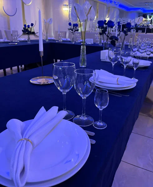 Güzel bir yemek masası, porselenler, şarap bardakları ve peçeteler düzgünce düzenlenmiş. Zarif masa düzeni yemek alanının sofistike atmosferini vurgular..