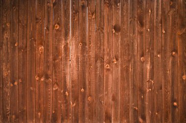 Doğal desenli yüzeyi olan ahşap tahtalardan yapılmış taşralı kahverengi çitler. Soyut arkaplan. Kereste duvarının kırsal kesim tarzıyla doğal arkaplan olarak kullanılan yakın çekimi.