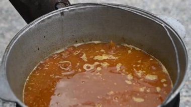 Köpüren çorba demliğine yakın çekim, yükselen buharlı çorbayı gösteriyor. Malzemeler kaynaşıyor, aromalı ve aromatik sıvı oluşturuyor. Kaynar çorba demliği, kaynayan sıvıdan yükselen buhar..