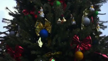 Dönen Noel ağacının yakın çekimi, altın fiyonklarla parıldayan süslemeler ve renkli mücevherler. Şenlik süsleri ve kurdelelerin sihirli gösterisi. Kurdeleler ve parlak dekoratif toplar. xmas arkaplanı.