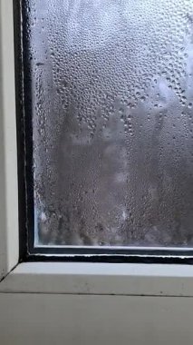 Yoğunlaşmış pencere. Cam su damlacıklarıyla kaplıdır. Dairede nem var. dikey video.
