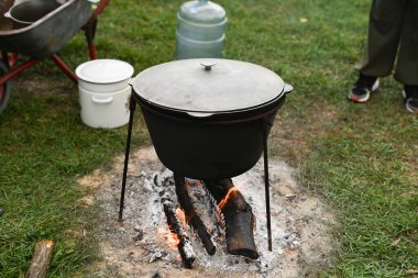 Dumanı ve alevi görünür bir şekilde açık ateşin üzerine yerleştirilmiş tencere. Doğal ortamlarda yerde geleneksel yemek hazırlamak için kullanılan kazan. Yaşam tarzı gıda konsepti. Büyük kazan.