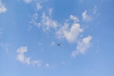 Helikopter, açık havada süzülen yumuşak bulutlu, parlak mavi gökyüzüne karşı yakalandı. Helikopter, ulaşım, kurtarma ya da seyahat konseptini simgeliyor..