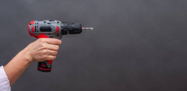 Kablosuz matkap, kısa metalik ucu olan elektrikli alet, izole edilmiş gri arka plan, DIY için profesyonel ve ev aletleri. Tek elle tutturulmuş kablosuz matkap, kırmızı ve siyah araç.