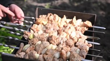 Kebap sıcak kömür ızgarasının üzerinde metal şiş açıyor. Eller yemek pişirirken kebabı döndürür. Duman ve ısıya yakın kebap, doğal ışık, barbekü yemek yaşam tarzı konsepti.
