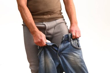 Adamın termal iç çamaşırının üstüne pantolon giydiği yakın plan fotoğraf. Kışın konfor ve soğuk hava ortamlarında sıcaklık için kıyafet katmanı kavramı. İnsan uzun pantolonlar üzerine kot giyer. izole edilmiş beyaz.