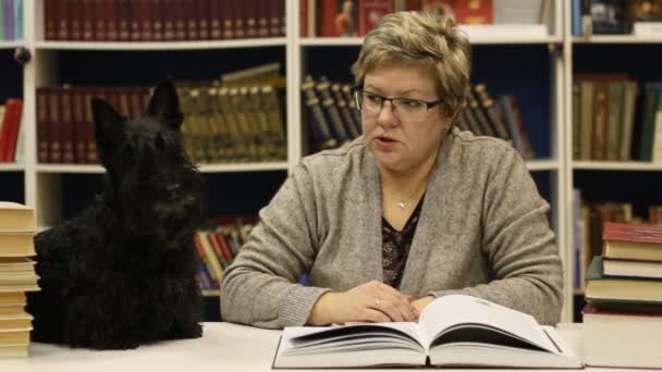 Kvinna läser en bok för hunden — Stockvideo