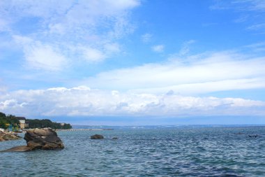 Denizde güneşli bir gün, beyaz bulutlu..