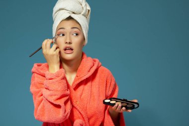 Genç ve çekici bir kadın mavi arka plan üzerine göz kapaklarını kapatıyor. Çekici kız sabah güzellik ve makyaj yapıyor.