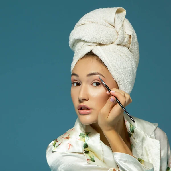 Mujer Atractiva Joven Poniendo Tono Sus Cejas Sobre Fondo Azul —  Fotos de Stock
