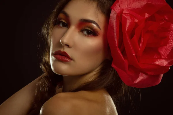 Vintage portrait of fashion glamour girl with red flower in her hair, over black. Studio shot. Spanish Carmen style