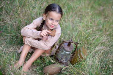 Uzun at kuyruklu ve güzel kirli yüzlü güzel bir kız. Yaz çayırında eski model parafin sobasıyla oturuyor ve bayat ekmek yiyor. Yetim, savaş çocuğu, yoksulluk, açlık, kıtlık, yoksul çocuk. 