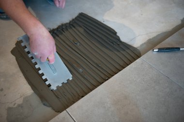 Tiler seramik fayansı yere seriyor. Profesyonel işçi tadilat yapıyor. İnşaat. Tetler 'in elleri. Ev yenileme ve yeni ev inşa etme