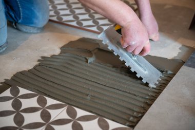 Tiler seramik fayansı yere seriyor. Profesyonel işçi tadilat yapıyor. İnşaat. Tetler 'in elleri. Ev yenileme ve yeni ev inşa etme