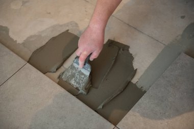 Tiler seramik fayansı yere seriyor. Profesyonel işçi tadilat yapıyor. İnşaat. Tetler 'in elleri. Ev yenileme ve yeni ev inşa etme