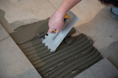 Tiler seramik fayansı yere seriyor. Profesyonel işçi tadilat yapıyor. İnşaat. Tetler 'in elleri. Ev yenileme ve yeni ev inşa etme