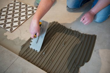 Tiler seramik fayansı yere seriyor. Profesyonel işçi tadilat yapıyor. İnşaat. Tetler 'in elleri. Ev yenileme ve yeni ev inşa etme