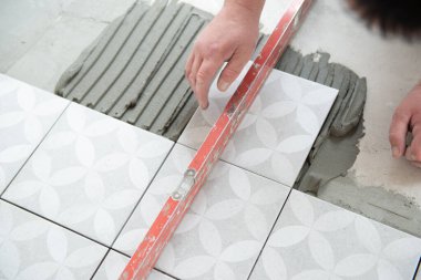 Tiler laying the ceramic tile on the floor. Professional worker makes renovation. Construction. Hands of the tiler. Home renovation and building new house clipart