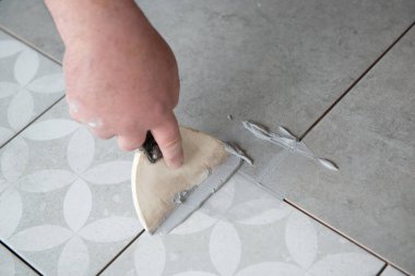 Tiler laying the ceramic tile on the floor. Professional worker makes renovation. Construction. Hands of the tiler. Home renovation and building new house clipart