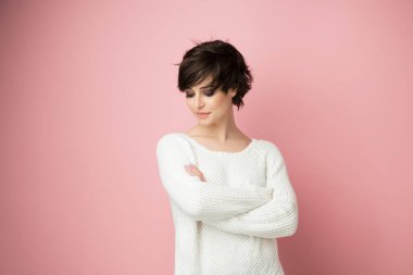 Stüdyoda pembe arka planda poz veren güzel genç bir bayan. Telif uzayına bakıyor. Güzel esmer kadın portresi. 