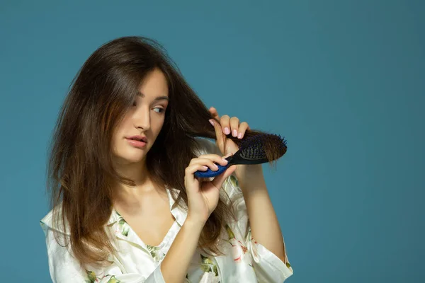 Wesoła Atrakcyjna Nastolatka Grzebie Włosy Nad Niebieskim Tłem Niezręczne Włosy — Zdjęcie stockowe
